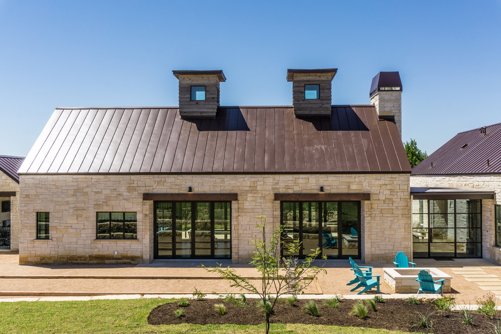Inspiration for a large country one-storey beige house exterior in Austin with stone veneer and a metal roof.