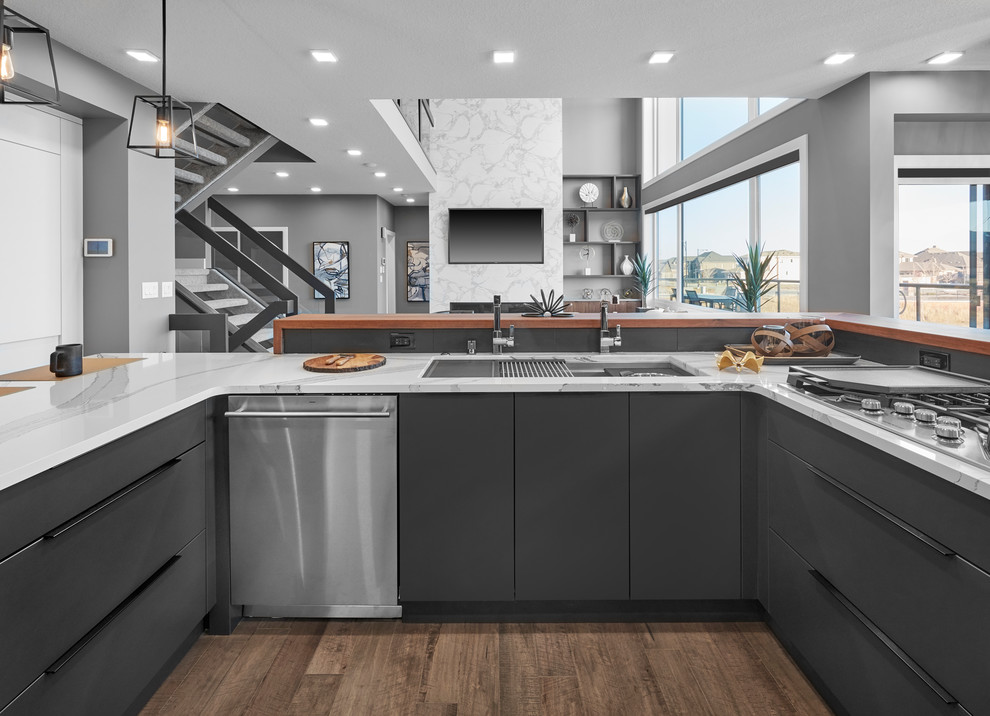 Large contemporary u-shaped eat-in kitchen in Edmonton with an undermount sink, louvered cabinets, white cabinets, wood benchtops, grey splashback, porcelain splashback, stainless steel appliances, medium hardwood floors, with island, brown floor and brown benchtop.