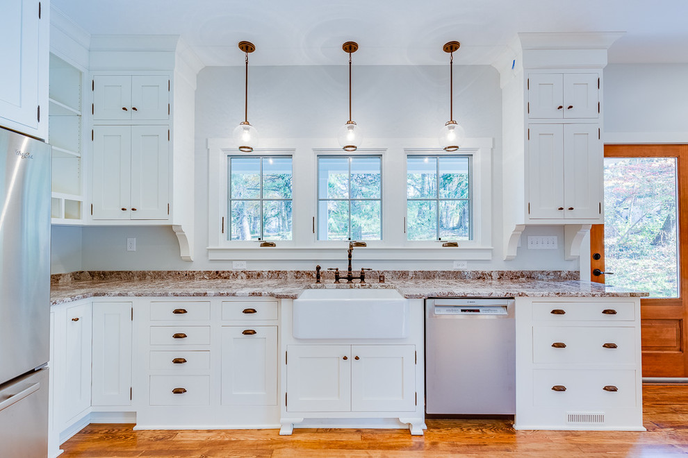 Photo of a mid-sized country kitchen in Louisville with a farmhouse sink, shaker cabinets, white cabinets, granite benchtops, stainless steel appliances and light hardwood floors.