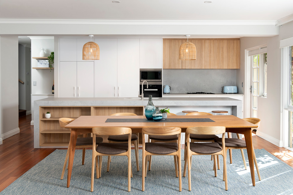 This is an example of a contemporary galley eat-in kitchen in Perth with an undermount sink, flat-panel cabinets, white cabinets, grey splashback, stainless steel appliances, medium hardwood floors, with island, brown floor and grey benchtop.