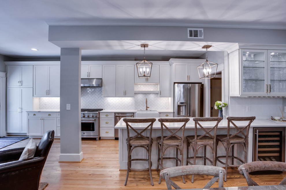 Inspiration for a mid-sized transitional galley light wood floor and beige floor eat-in kitchen remodel in DC Metro with a farmhouse sink, shaker cabinets, white cabinets, quartz countertops, white backsplash, subway tile backsplash, stainless steel appliances, a peninsula and white countertops