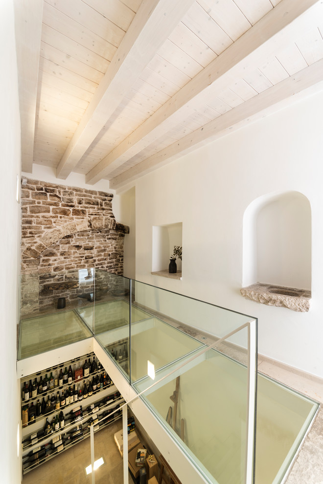 Inspiration for a small midcentury wine cellar in Bari with limestone floors, display racks and beige floor.
