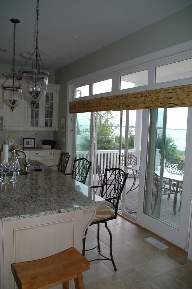 Photo of a mid-sized beach style u-shaped separate kitchen in New York with recessed-panel cabinets, beige cabinets, granite benchtops, beige splashback, terra-cotta floors and with island.