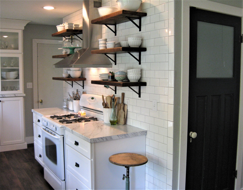Design ideas for a small country galley separate kitchen with a drop-in sink, shaker cabinets, white cabinets, laminate benchtops, white splashback, subway tile splashback, white appliances, medium hardwood floors, no island, brown floor and white benchtop.