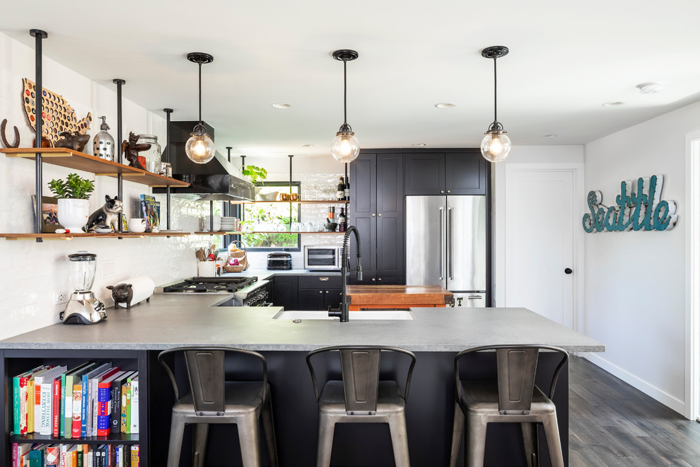 Mid-sized contemporary u-shaped open plan kitchen in Seattle with a farmhouse sink, shaker cabinets, black cabinets, quartz benchtops, white splashback, porcelain splashback, stainless steel appliances, dark hardwood floors, a peninsula and grey benchtop.