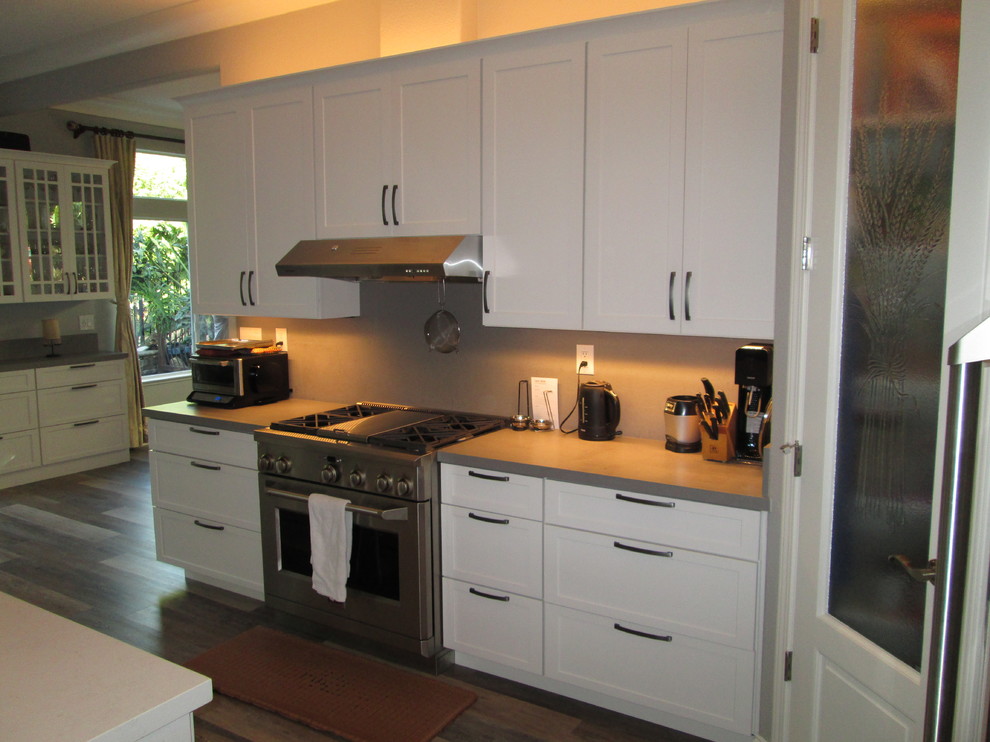 Large contemporary galley eat-in kitchen in San Francisco with an undermount sink, shaker cabinets, quartz benchtops, stainless steel appliances, vinyl floors, with island, stainless steel cabinets and beige splashback.