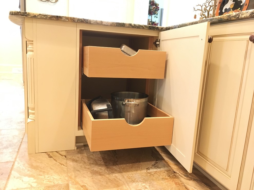 Example of a large transitional galley porcelain tile enclosed kitchen design with an undermount sink, raised-panel cabinets, distressed cabinets, granite countertops, beige backsplash, stone tile backsplash, stainless steel appliances and a peninsula