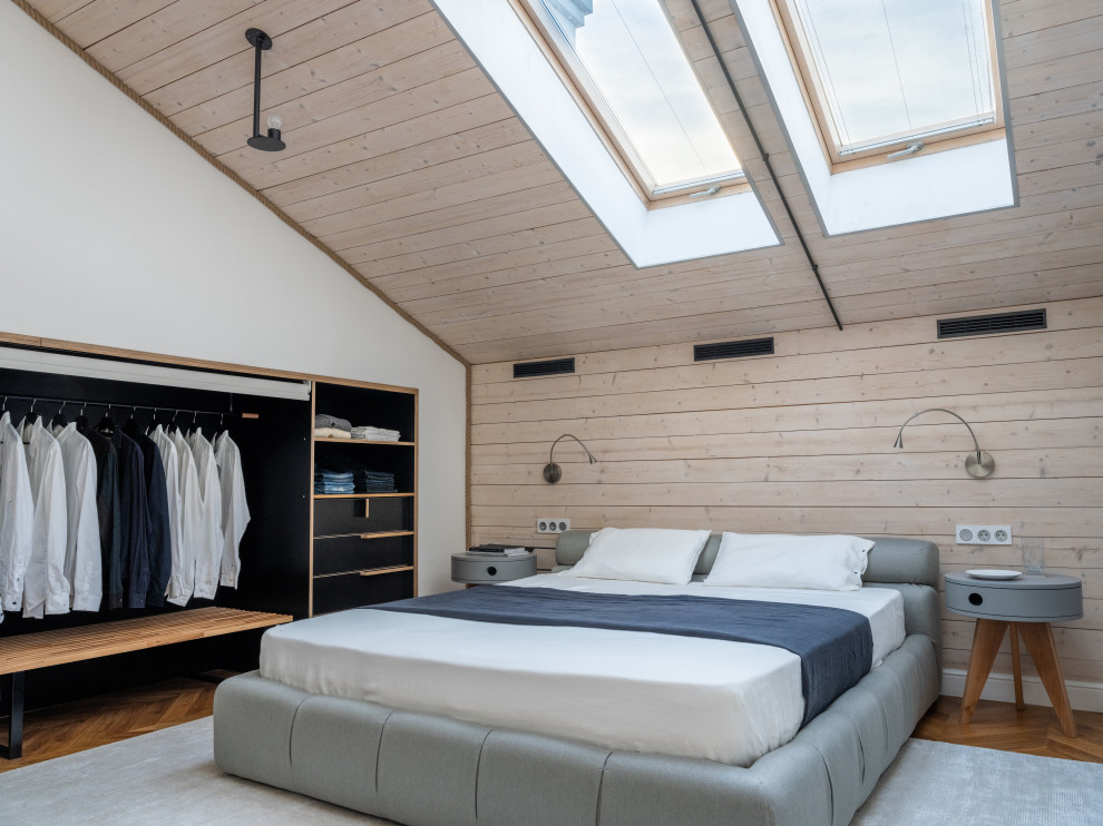 Cette image montre une chambre parentale avec un mur blanc, un sol en bois brun, un sol marron et un plafond en lambris de bois.
