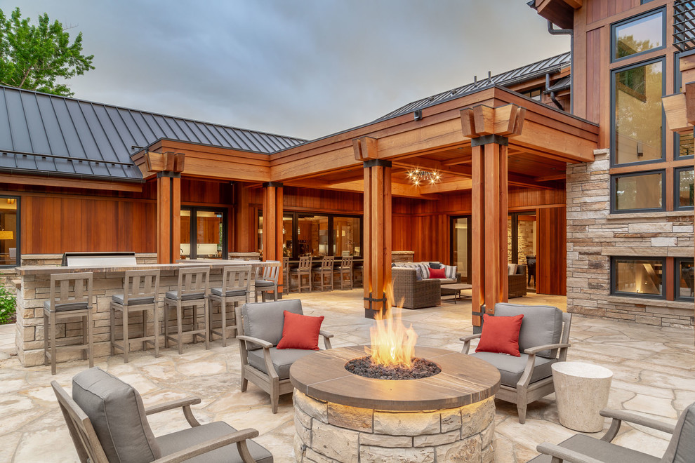 Country patio in Denver with a fire feature, natural stone pavers and no cover.