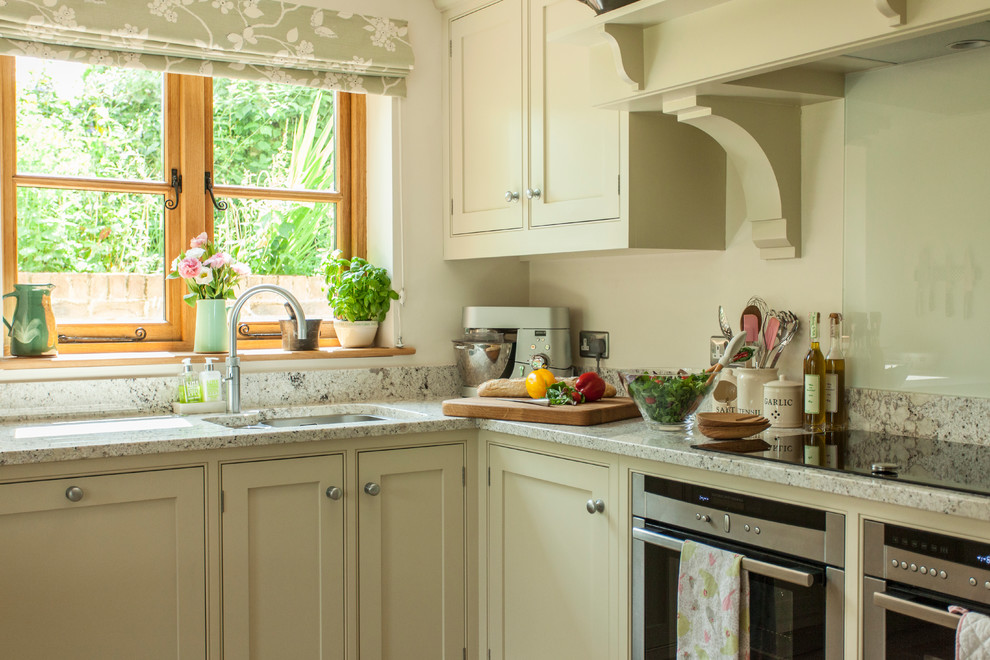 Inspiration for a large traditional l-shaped eat-in kitchen in Gloucestershire with a drop-in sink, shaker cabinets, green cabinets, granite benchtops, white splashback, glass sheet splashback, stainless steel appliances, travertine floors, with island, beige floor and green benchtop.