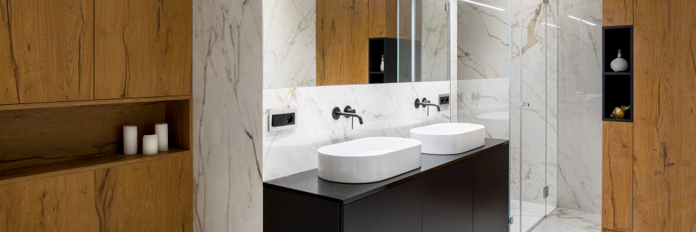 Mid-sized contemporary bathroom in Tampa with a freestanding tub, black and white tile, stone slab, a niche, a double vanity, wood walls, flat-panel cabinets, black cabinets, white walls, marble floors, a vessel sink, a hinged shower door and a built-in vanity.