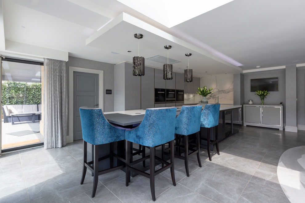 Design ideas for a large contemporary l-shaped open plan kitchen in Cheshire with flat-panel cabinets, grey cabinets, white splashback, marble splashback, black appliances, porcelain floors, with island, grey floor and white benchtop.