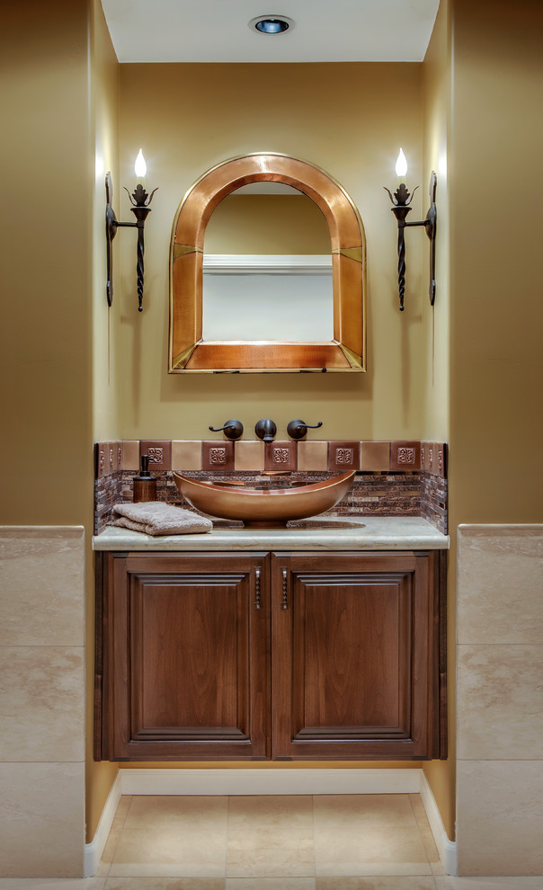 Small traditional powder room in Phoenix with raised-panel cabinets, dark wood cabinets, a one-piece toilet, multi-coloured tile, yellow walls, travertine floors, a vessel sink, marble benchtops, matchstick tile and grey benchtops.