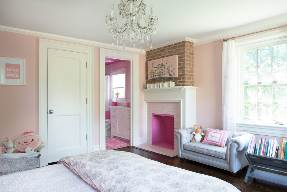 Photo of a large transitional kids' bedroom for kids 4-10 years old and girls in New York with pink walls and dark hardwood floors.