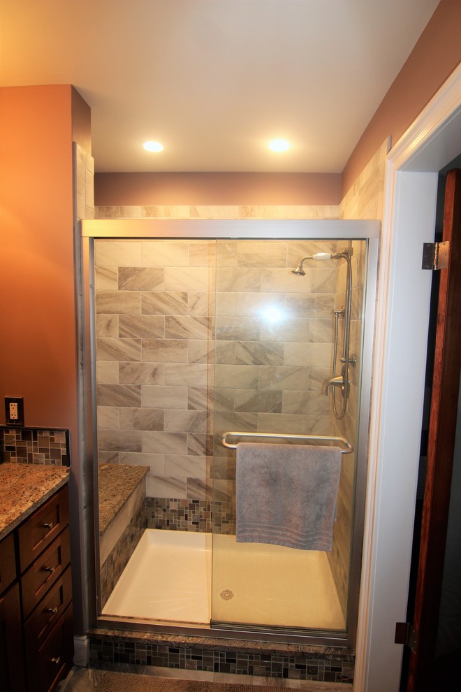 Mid-sized modern master bathroom in Baltimore with recessed-panel cabinets, medium wood cabinets, a shower/bathtub combo, a one-piece toilet, black tile, ceramic tile, blue walls, ceramic floors, an undermount sink and granite benchtops.