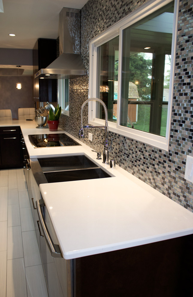 This is an example of a mid-sized contemporary single-wall eat-in kitchen in Milwaukee with a farmhouse sink, flat-panel cabinets, dark wood cabinets, quartzite benchtops, metallic splashback, glass tile splashback, stainless steel appliances, porcelain floors and no island.