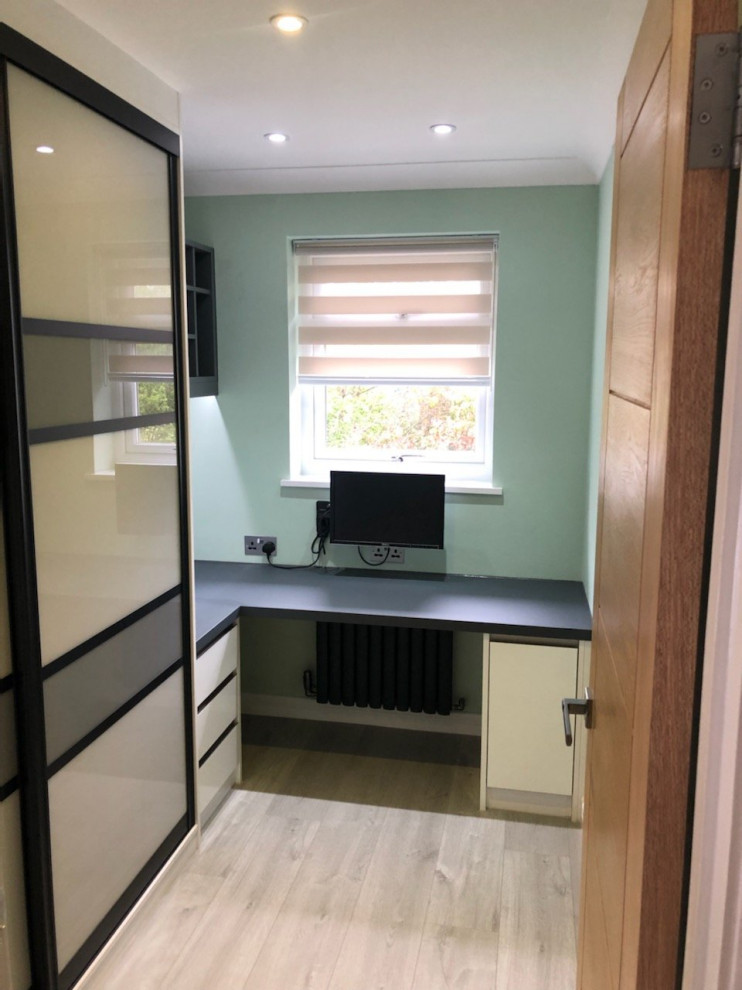 Photo of a small modern home office in Surrey with green walls, light hardwood flooring, a built-in desk and brown floors.