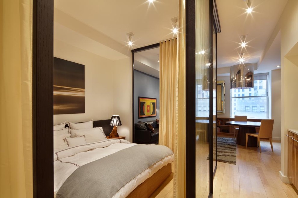 Contemporary bedroom in New York with white walls, light hardwood floors and no fireplace.