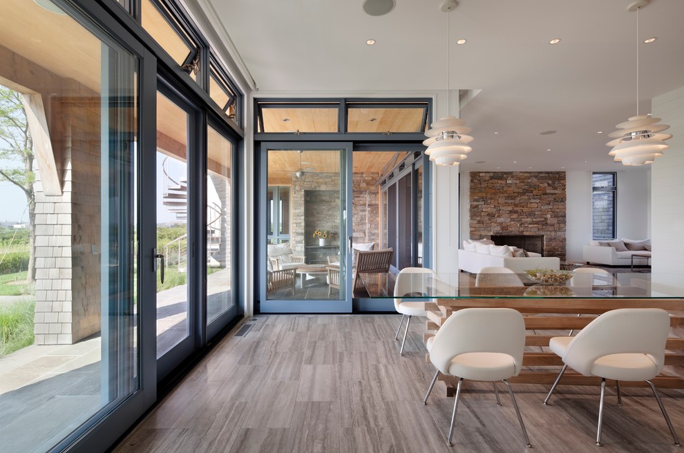 This is an example of an expansive contemporary open plan dining in New York with white walls, laminate floors, no fireplace and brown floor.