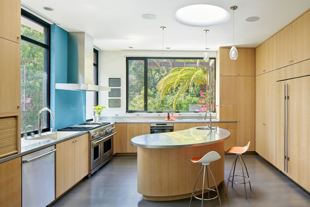 Inspiration for a midcentury u-shaped eat-in kitchen in San Francisco with an integrated sink, flat-panel cabinets, light wood cabinets, stainless steel benchtops, blue splashback, glass sheet splashback, stainless steel appliances, with island, grey benchtop, medium hardwood floors and brown floor.