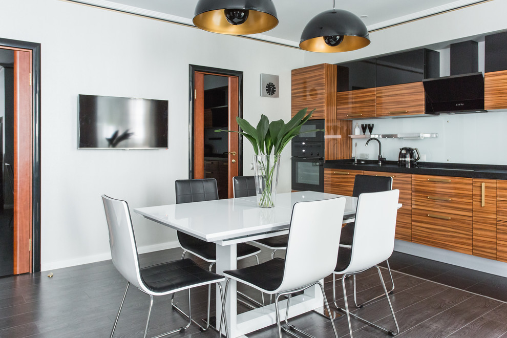 Photo of a mid-sized contemporary single-wall eat-in kitchen in Moscow with dark hardwood floors, flat-panel cabinets, medium wood cabinets, white splashback, black appliances and no island.