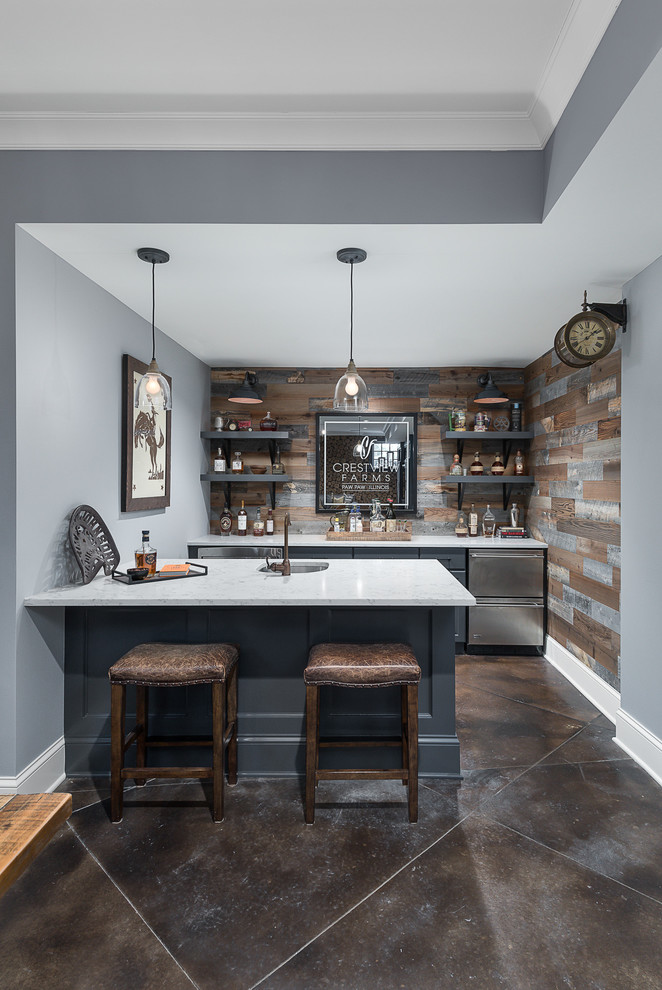 This is an example of a transitional galley home bar in Chicago with an undermount sink, recessed-panel cabinets, blue cabinets, multi-coloured splashback, timber splashback, brown floor and white benchtop.
