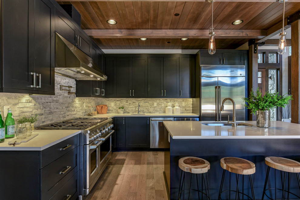 Design ideas for a country l-shaped kitchen in Seattle with an undermount sink, shaker cabinets, black cabinets, grey splashback, stainless steel appliances, medium hardwood floors, with island, brown floor and grey benchtop.