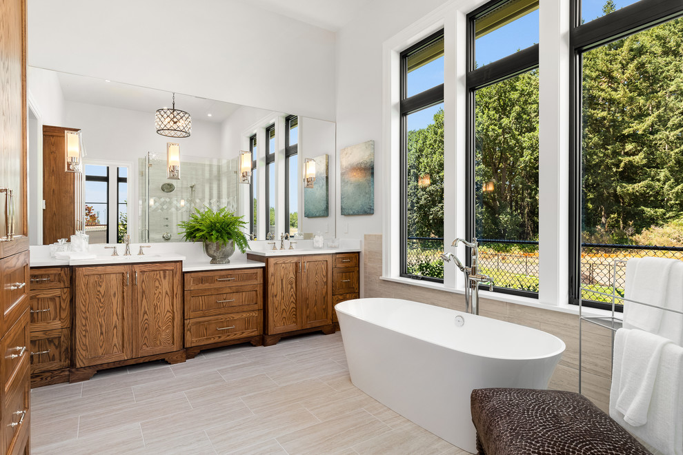 Photo of an expansive country master bathroom in Portland with shaker cabinets, medium wood cabinets, a freestanding tub, white walls, porcelain floors, an undermount sink, engineered quartz benchtops, grey floor and white benchtops.