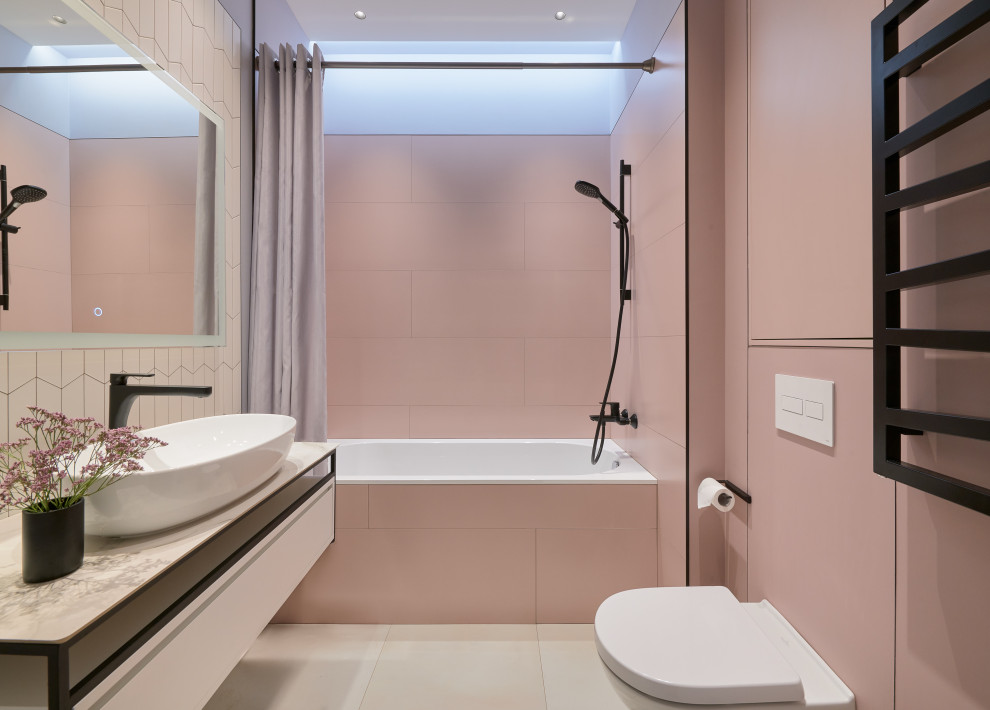 На фото: маленькая главная ванная комната в современном стиле с плоскими фасадами, белыми фасадами, ванной в нише, инсталляцией, розовой плиткой, керамогранитной плиткой, серыми стенами, полом из керамогранита, накладной раковиной, столешницей из плитки, серым полом, серой столешницей, нишей, тумбой под одну раковину, подвесной тумбой и многоуровневым потолком для на участке и в саду