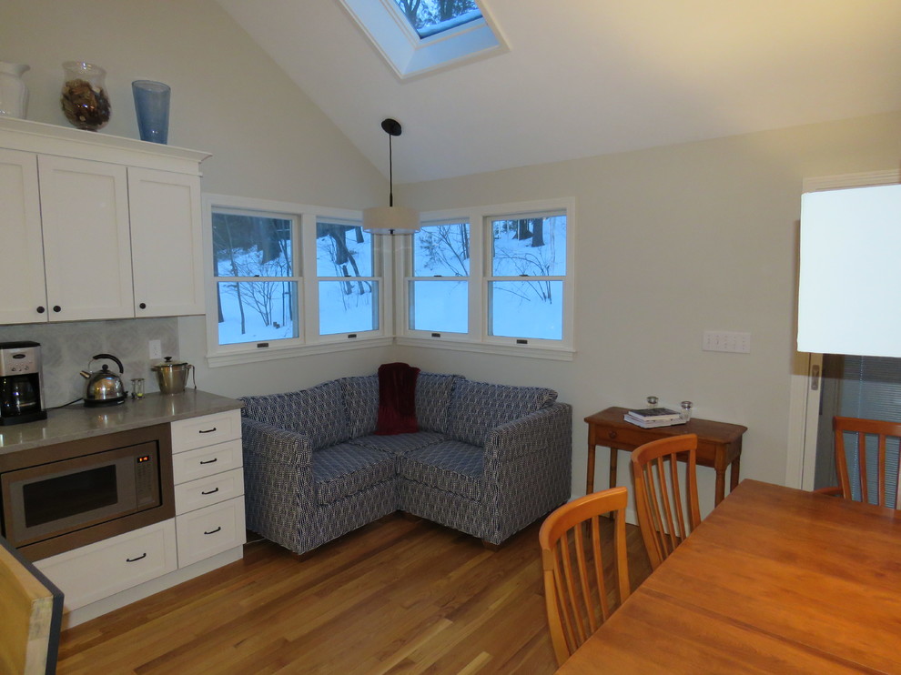 Inspiration for a large transitional l-shaped medium tone wood floor open concept kitchen remodel in Boston with an undermount sink, shaker cabinets, white cabinets, quartz countertops, gray backsplash, stainless steel appliances and an island