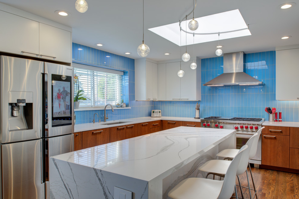 サンフランシスコにある高級な広いミッドセンチュリースタイルのおしゃれなキッチン (アンダーカウンターシンク、フラットパネル扉のキャビネット、中間色木目調キャビネット、クオーツストーンカウンター、青いキッチンパネル、ガラスタイルのキッチンパネル、シルバーの調理設備、濃色無垢フローリング、茶色い床、白いキッチンカウンター) の写真