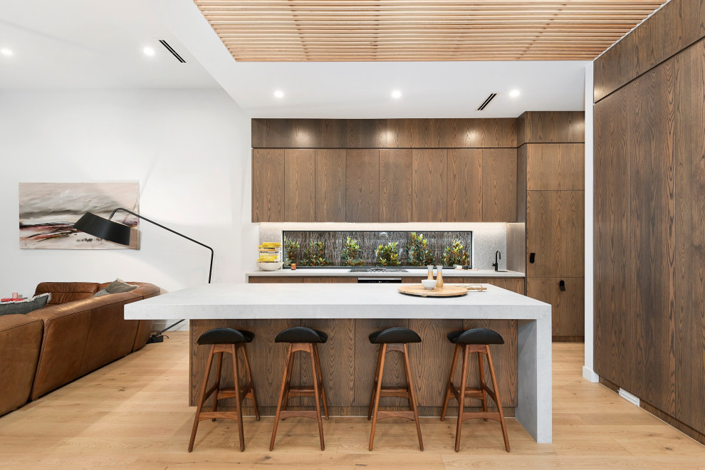 Large contemporary galley open plan kitchen in Melbourne with an undermount sink, flat-panel cabinets, medium wood cabinets, grey splashback, medium hardwood floors, with island, beige floor, grey benchtop and wood.