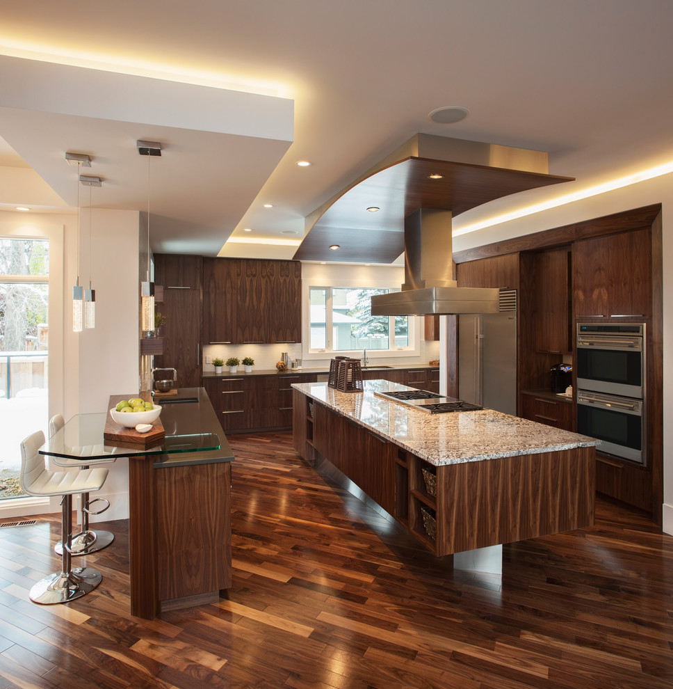 Photo of a contemporary kitchen in Calgary with stainless steel appliances, flat-panel cabinets, dark wood cabinets and brown floor.