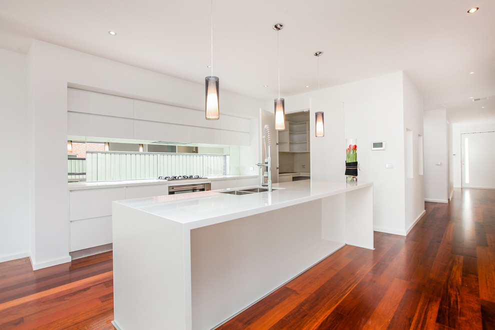This is an example of a modern kitchen in Melbourne with white cabinets, stainless steel appliances and with island.