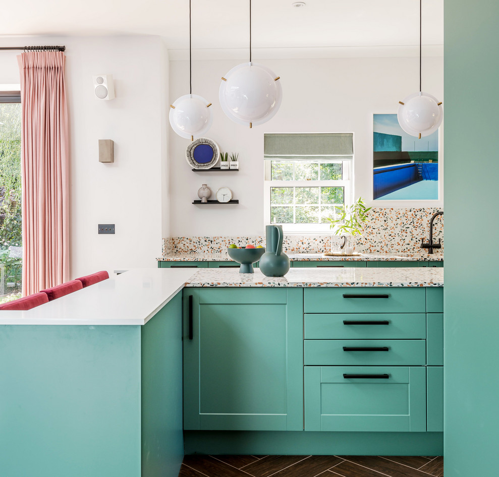 Contemporary l-shaped kitchen in London with shaker cabinets, turquoise cabinets, terrazzo benchtops, multi-coloured splashback, with island, brown floor and multi-coloured benchtop.