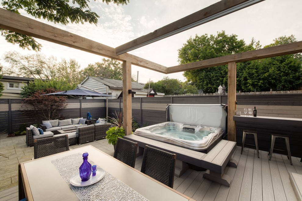 Small modern backyard deck in Toronto with a fire feature and a pergola.