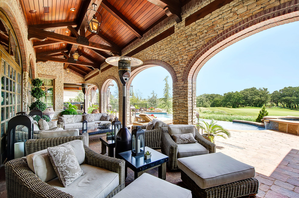 This is an example of a mediterranean backyard verandah in Dallas with brick pavers and a roof extension.
