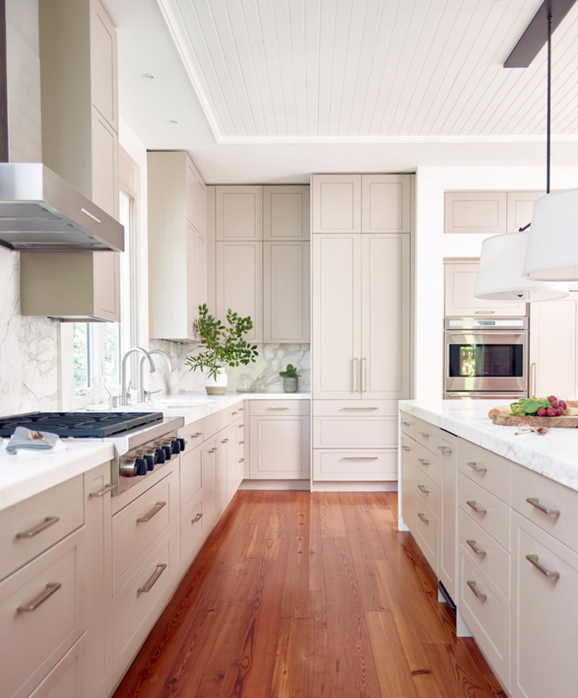 Foto på ett stort vintage kök, med en undermonterad diskho, luckor med infälld panel, grå skåp, marmorbänkskiva, vitt stänkskydd, stänkskydd i marmor, rostfria vitvaror, mellanmörkt trägolv och en köksö