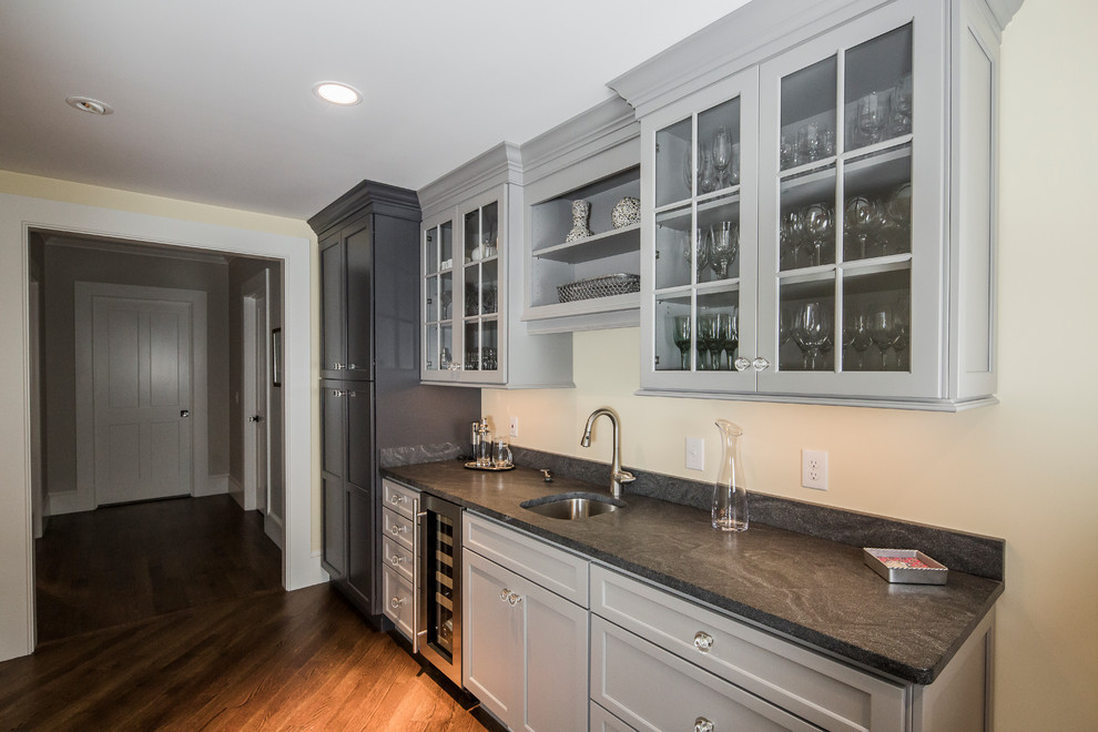 Inspiration for a large transitional single-wall dark wood floor eat-in kitchen remodel in Boston with an undermount sink, flat-panel cabinets, gray cabinets, granite countertops, white backsplash, ceramic backsplash, stainless steel appliances and an island