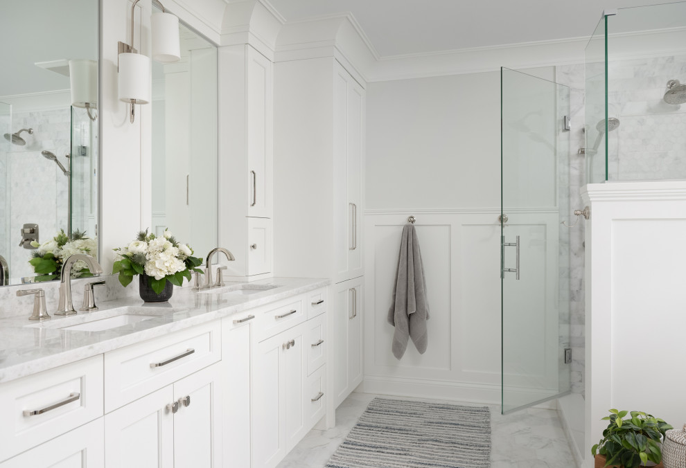 Design ideas for a mid-sized transitional master bathroom in Chicago with recessed-panel cabinets, white cabinets, a freestanding tub, a corner shower, a one-piece toilet, gray tile, marble, grey walls, marble floors, an undermount sink, marble benchtops, grey floor, a hinged shower door, grey benchtops, a niche, a double vanity, a built-in vanity and decorative wall panelling.