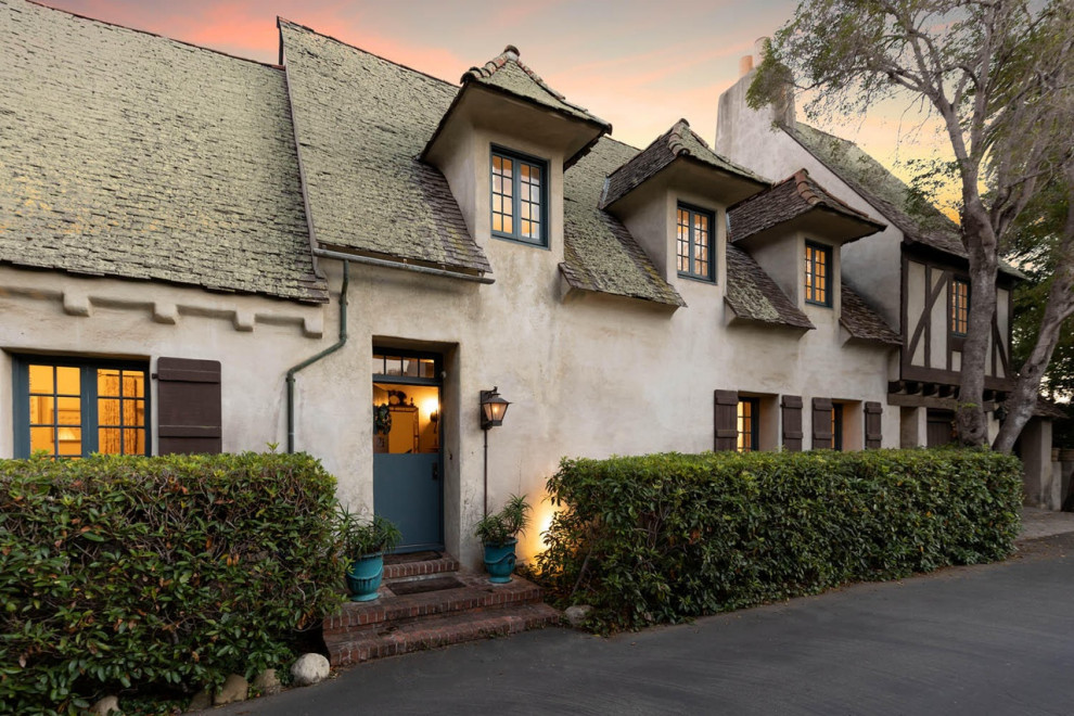 Design ideas for an expansive two-storey stucco beige house exterior in Santa Barbara with a gable roof, a shingle roof, a brown roof and shingle siding.
