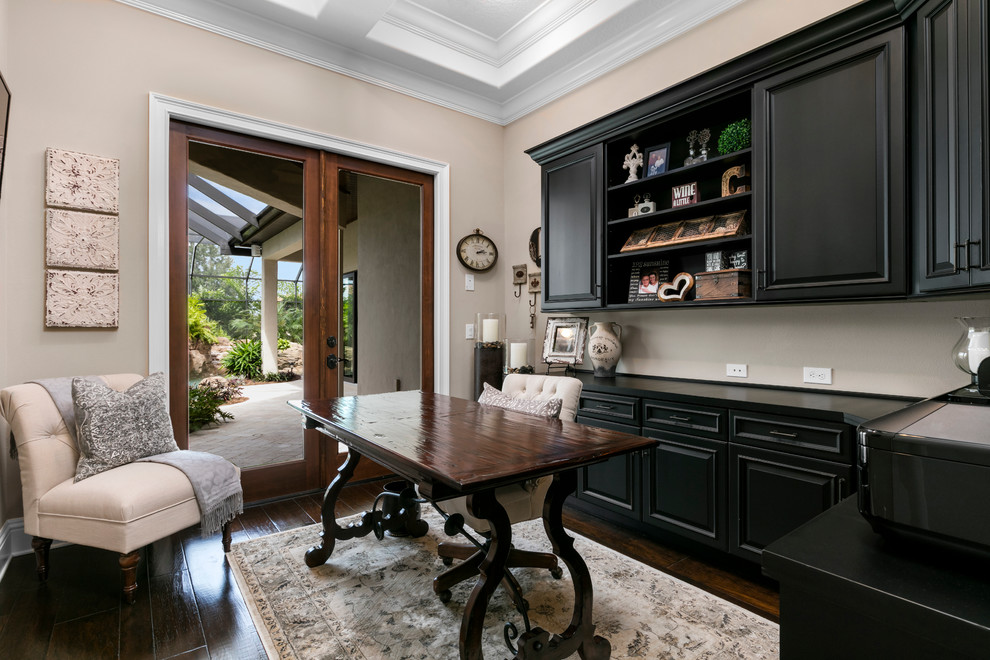 Mid-sized mediterranean study room in Orlando with beige walls, dark hardwood floors, a freestanding desk and no fireplace.