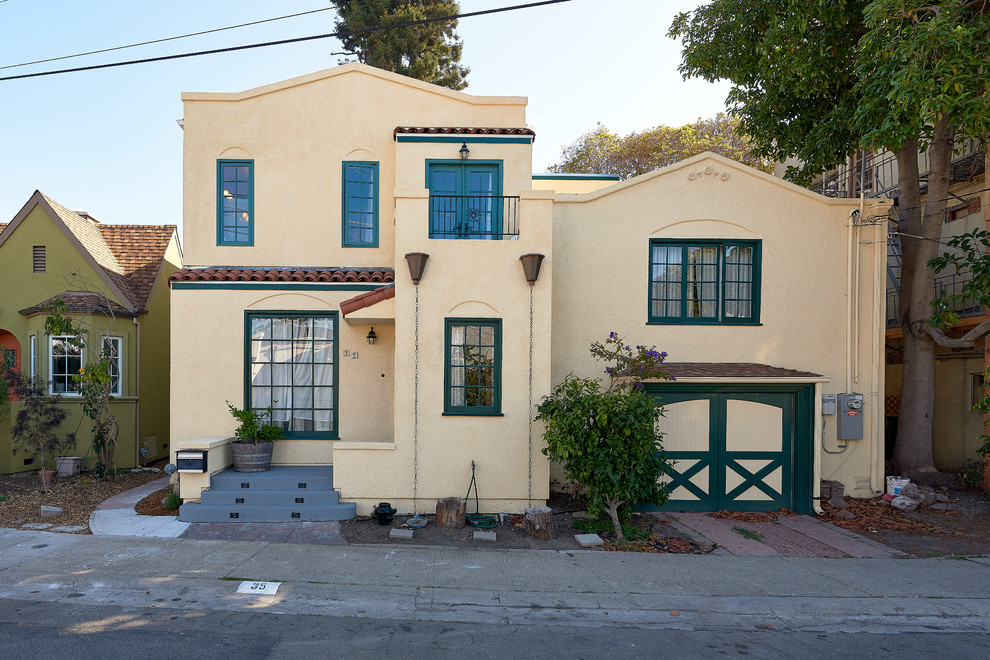 This is an example of a large transitional split-level stucco yellow house exterior in San Francisco with a flat roof and a tile roof.