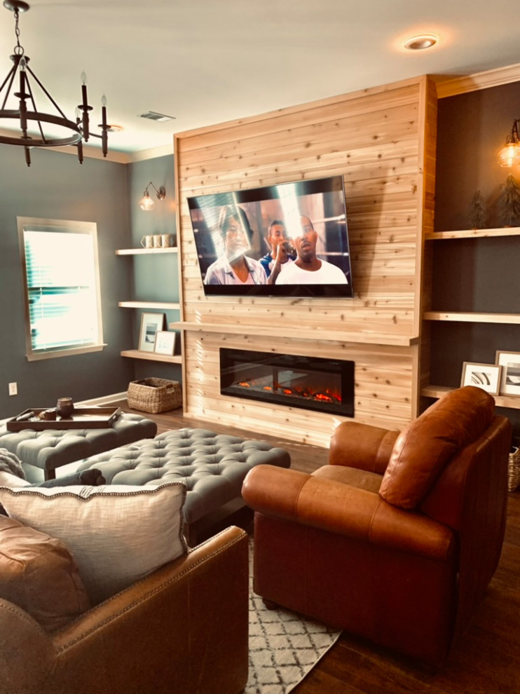 Cette image montre une grande salle de séjour craftsman fermée avec un bar de salon, un mur gris, un sol en vinyl, une cheminée standard, un manteau de cheminée en bois, un téléviseur fixé au mur, un sol marron, un plafond à caissons et boiseries.