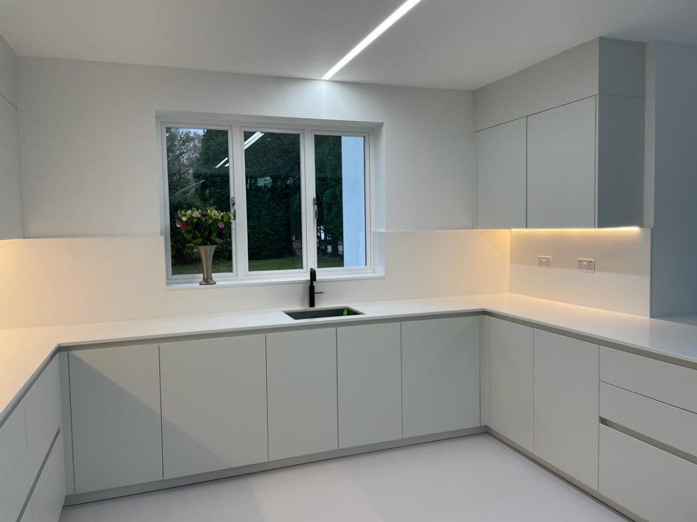 Idéer för att renovera ett litet funkis vit vitt kök, med en undermonterad diskho, luckor med profilerade fronter, vita skåp, bänkskiva i kvartsit, vitt stänkskydd, svarta vitvaror och vitt golv