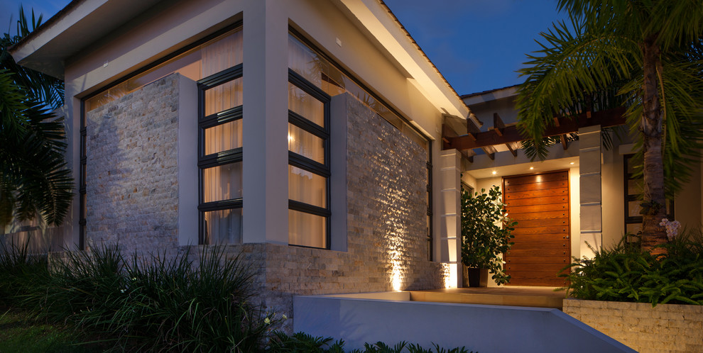 Photo of a large contemporary one-storey beige exterior in Other with stone veneer.