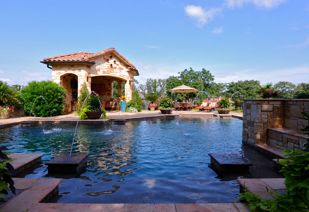 Design ideas for a large mediterranean custom-shaped pool in Dallas with natural stone pavers and a water feature.