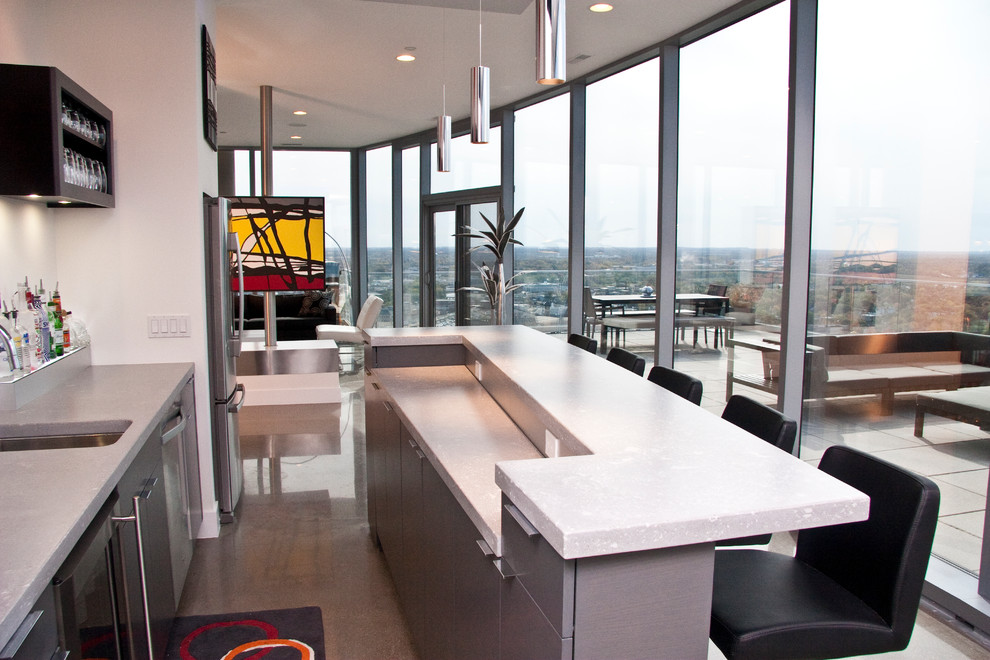 This is an example of a mid-sized contemporary galley home bar in Grand Rapids with an undermount sink, flat-panel cabinets, grey cabinets, quartz benchtops, concrete floors, grey floor and grey benchtop.