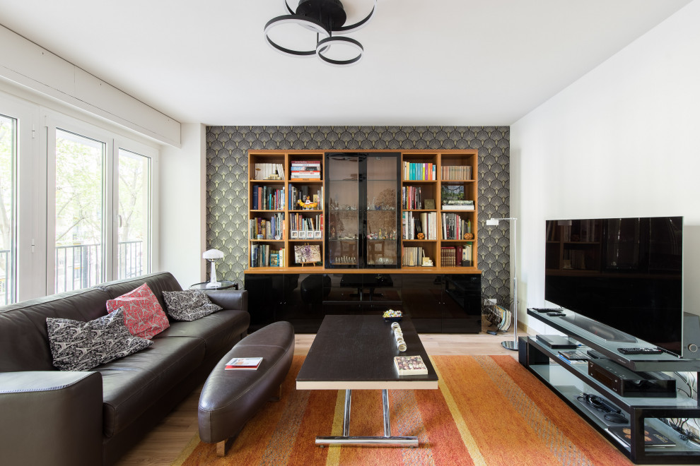 Exemple d'une grande salle de séjour tendance ouverte avec une bibliothèque ou un coin lecture, un mur noir, parquet clair, aucune cheminée, un téléviseur indépendant, un sol beige, du papier peint et canapé noir.