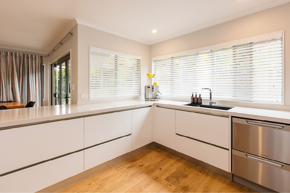 Inspiration for a large transitional l-shaped eat-in kitchen in Hamilton with an undermount sink, white cabinets, quartz benchtops, white splashback, glass sheet splashback, stainless steel appliances, light hardwood floors and no island.